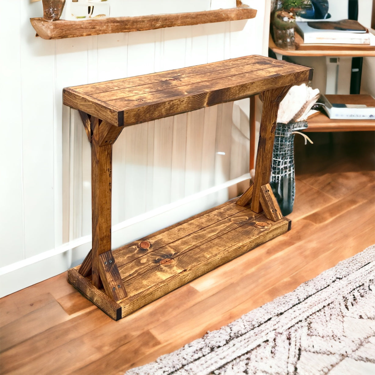 Wooden console table in a room with a rug and shelves.