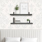 Decorative wall shelves with plants and a framed picture against a patterned wallpaper.